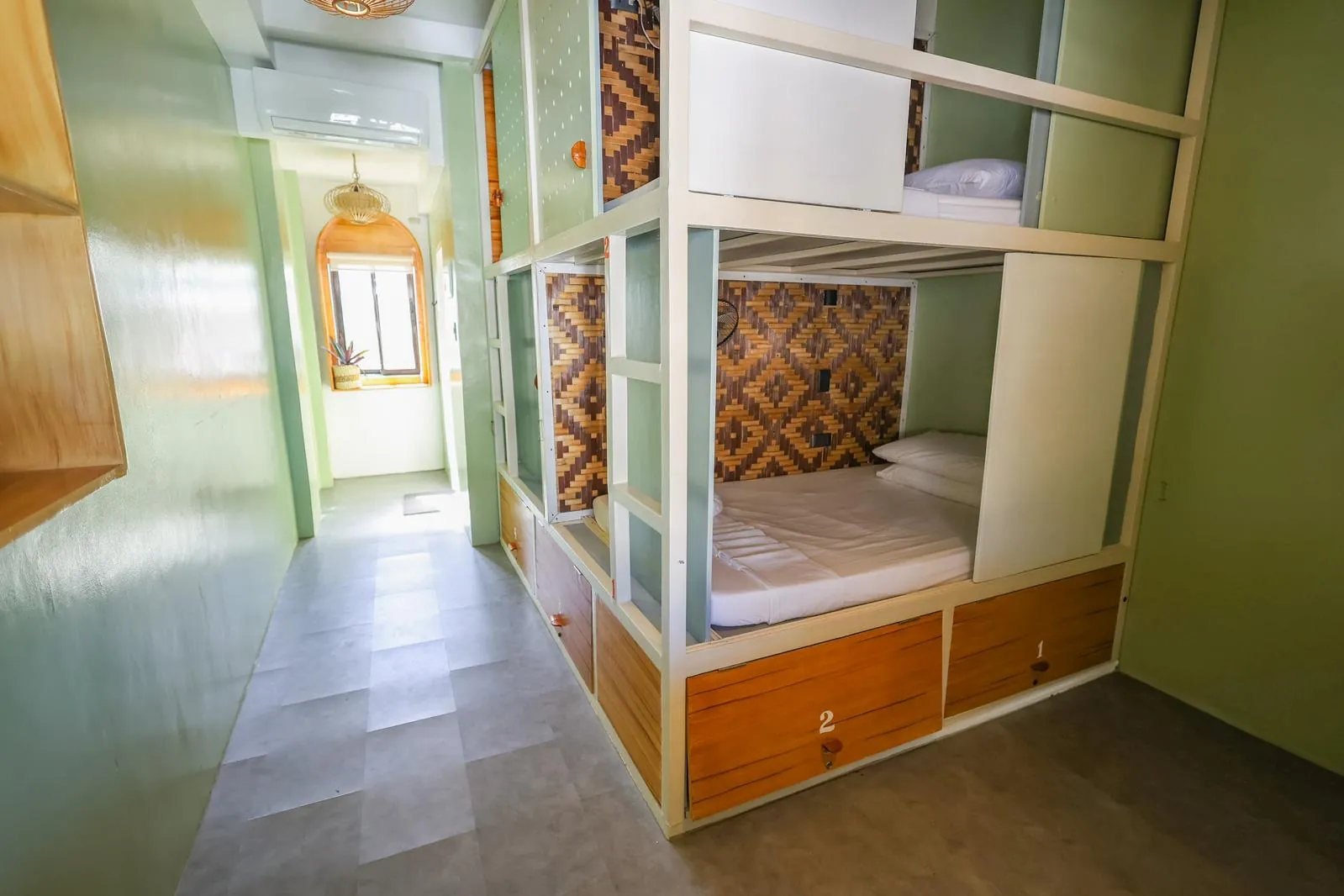 A bright room with built-in bunks, warm wood and soft green walls