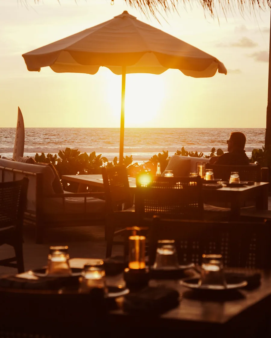 Drinks under a thatched umbrella at a beach bar at sunset