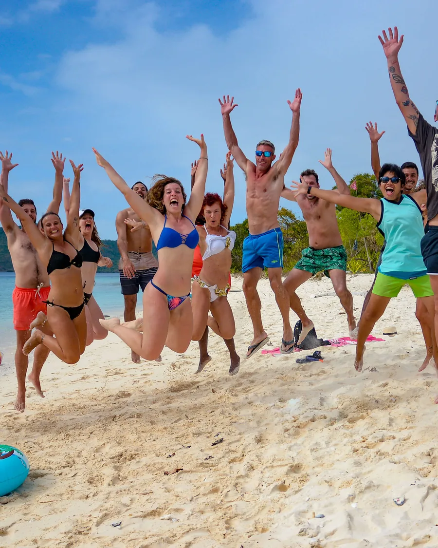 Guests jumping together on a white sand beach