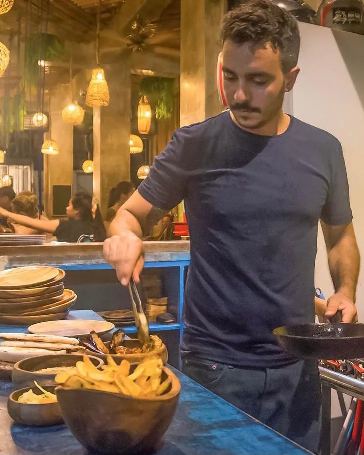 A Happiness chef plating food in the kitchen