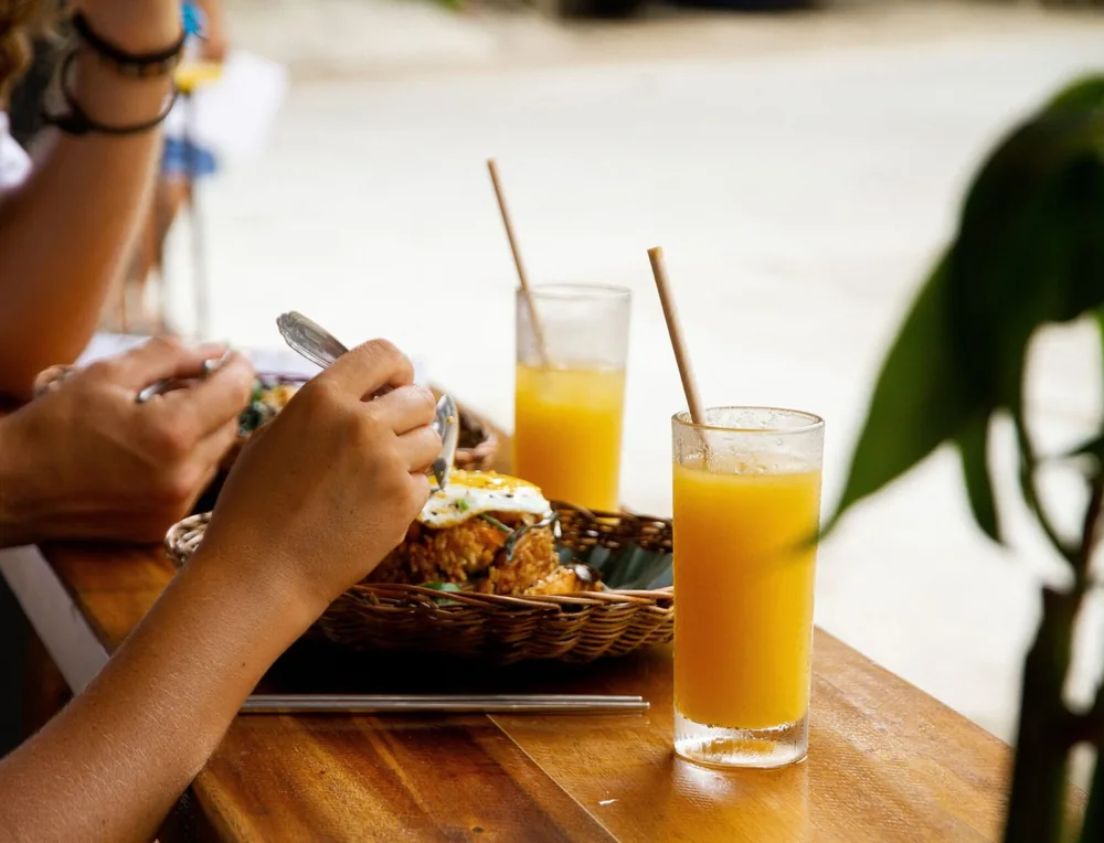 Brunch plates and fresh mango juice at a Happiness table in El Nido