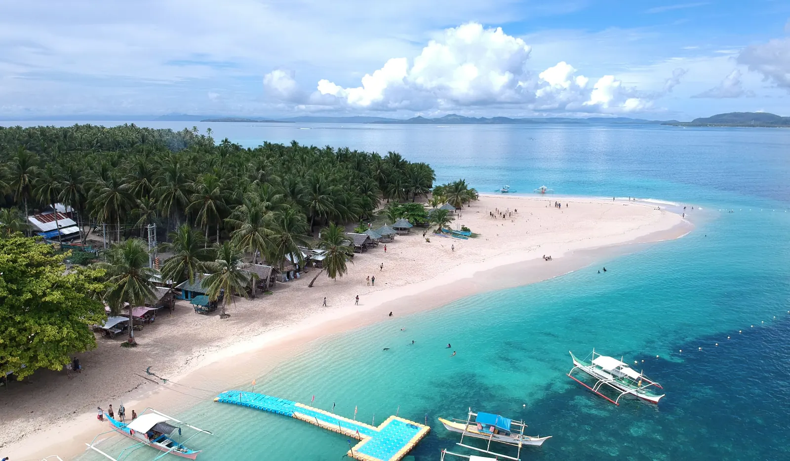 Island hopping in Siargao: white sand, palms and bangka boats in turquoise water
