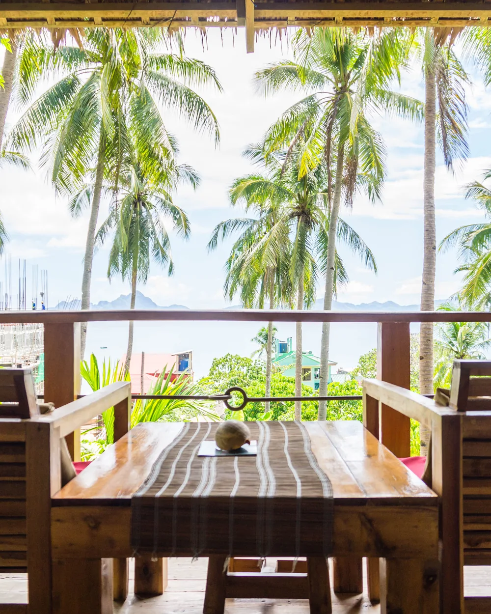 A shaded wooden terrace looking through the palms in El Nido