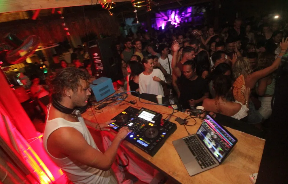 A DJ playing for a dancing crowd at night