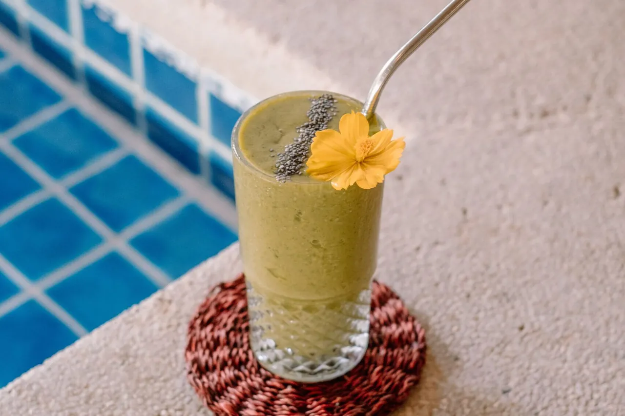 A mango smoothie by a blue tiled pool
