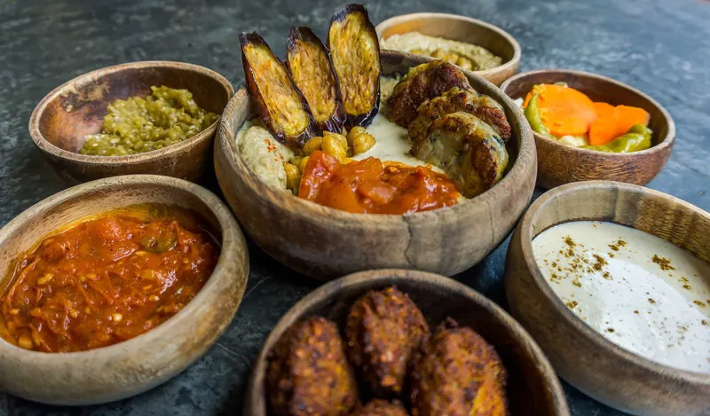 Bowls of curry, rice and grilled vegetables shared on a table