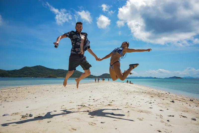 Two friends leaping high on a white-sand beach