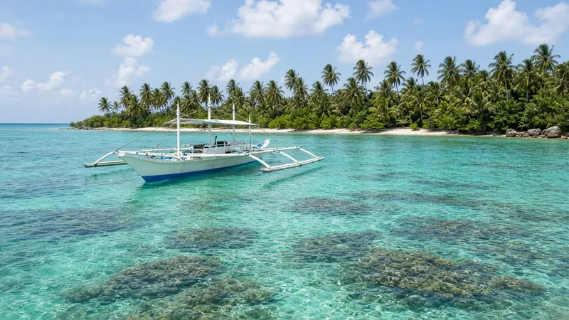 A bangka anchored over clear turquoise water and coral off Siargao
