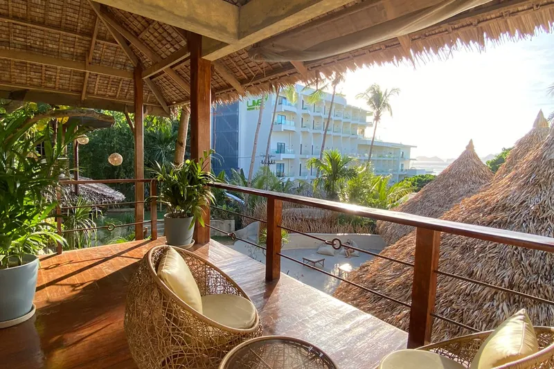 A shaded wooden balcony with rattan chairs at Happiness Beach Resort