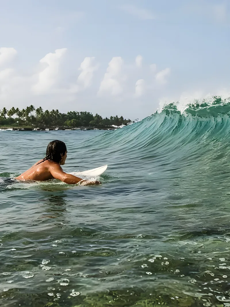 A surfer paddling for a small clean wave over the reef