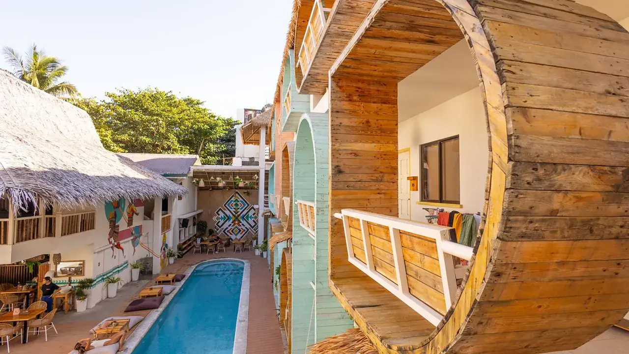 A round wooden window looking down onto the hostel pool