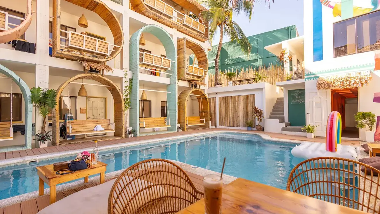 The hostel pool with a thatched cafe bar and colourful balconies