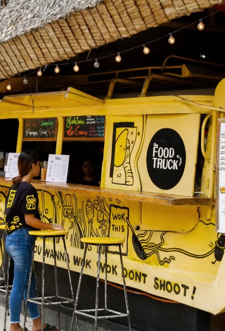 The yellow Happiness Food Truck with its signature truck art and bar stools