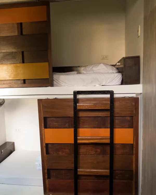 2-Bed Dorm: a bunk with its own ladder and wooden shutters