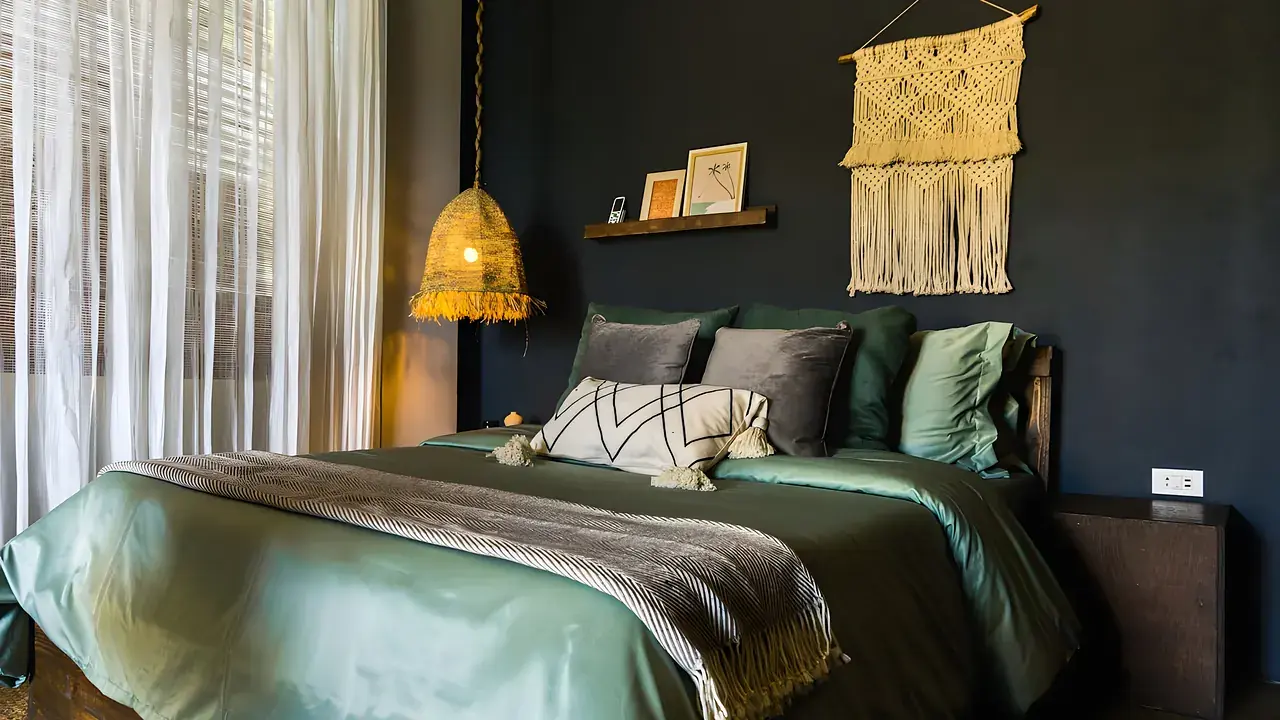 A villa bedroom with soft green linen and woven wall art