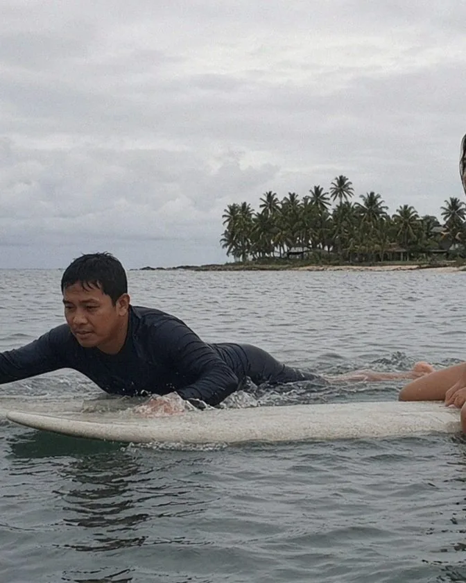 Coach and guest on surfboards in calm water off Siargao
